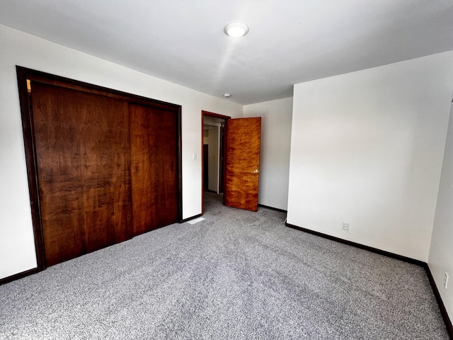 unfurnished bedroom featuring carpet floors, a closet, and baseboards