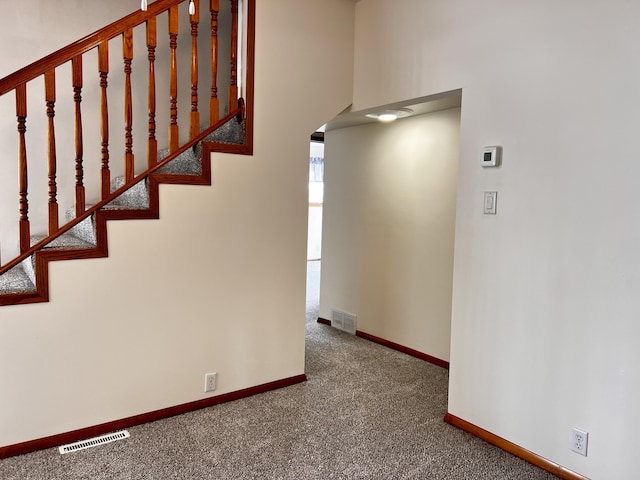 staircase with baseboards, visible vents, arched walkways, and carpet flooring