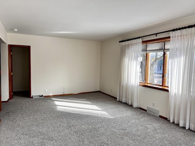 empty room with carpet, visible vents, and baseboards