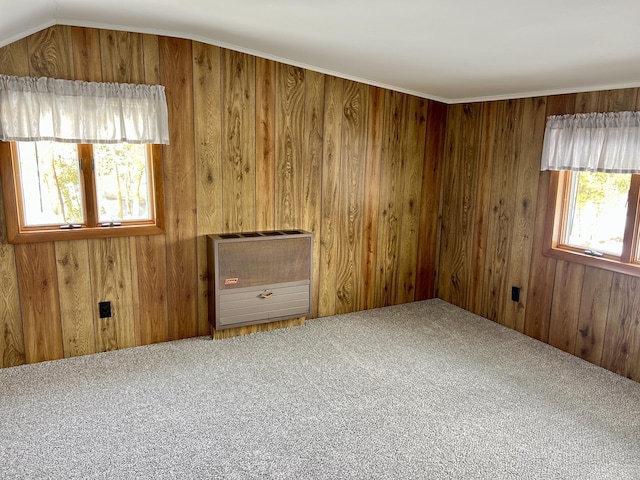 spare room with vaulted ceiling, wood walls, carpet flooring, and heating unit