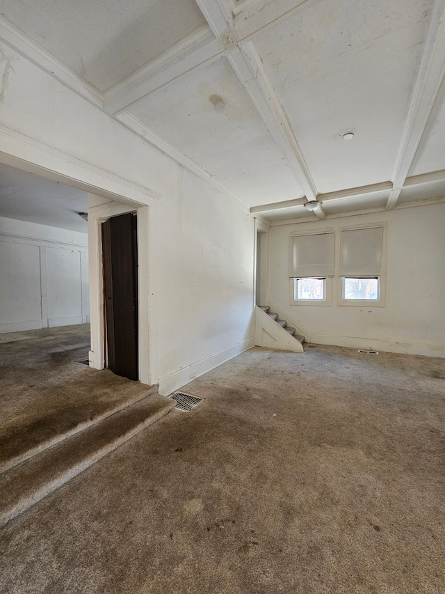 empty room featuring carpet, stairs, baseboards, and beam ceiling