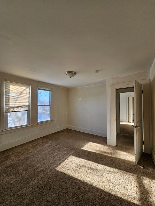 empty room with dark carpet and baseboards