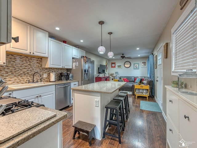 kitchen with stainless steel appliances, white cabinetry, open floor plan, a center island, and pendant lighting