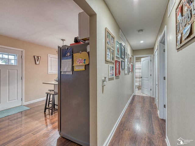 hall featuring visible vents, baseboards, and wood finished floors