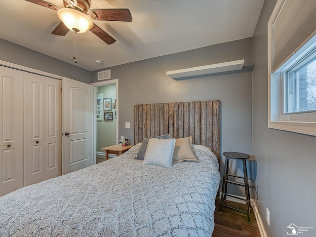 bedroom with dark wood-type flooring, a ceiling fan, visible vents, baseboards, and a closet