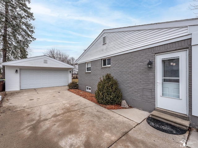 view of side of property featuring entry steps, brick siding, an outdoor structure, and a garage