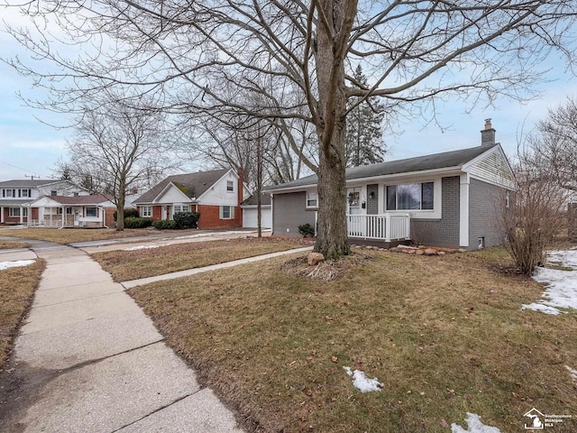 view of front of house featuring brick siding, a residential view, a chimney, a porch, and a front yard