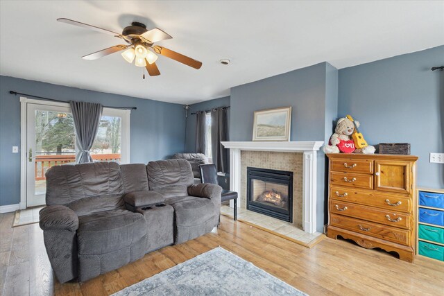 living area with baseboards, a ceiling fan, wood finished floors, and a tile fireplace