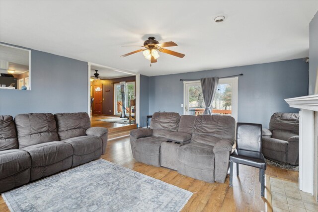 living room featuring a fireplace, wood finished floors, and a ceiling fan