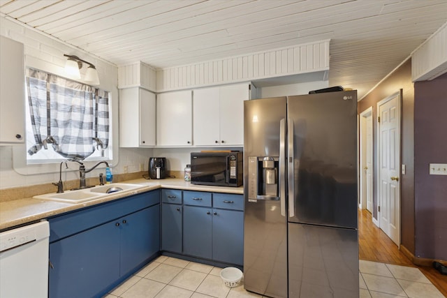 kitchen featuring black microwave, a sink, blue cabinetry, stainless steel refrigerator with ice dispenser, and dishwasher