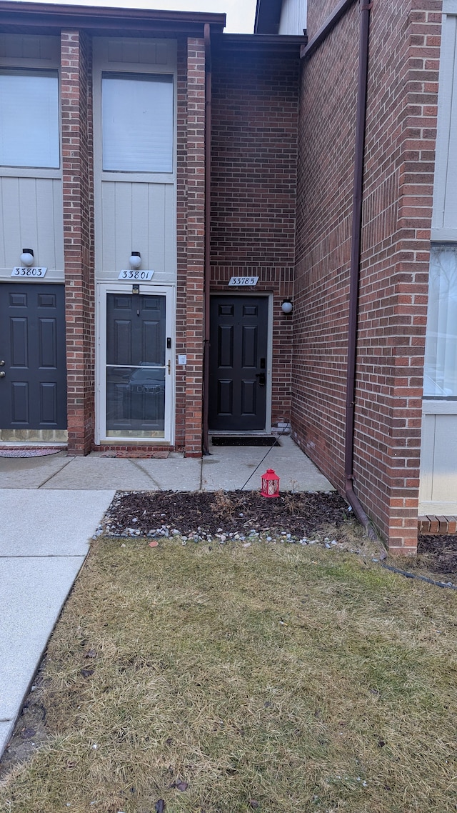 entrance to property with a lawn and brick siding