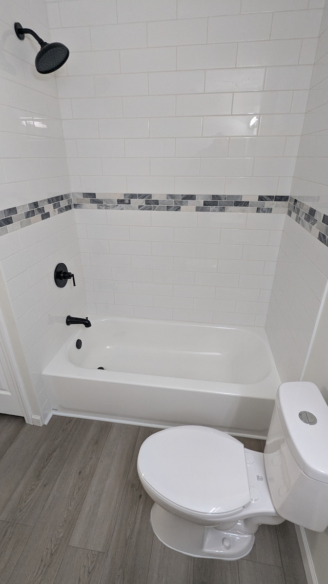 full bathroom featuring washtub / shower combination, toilet, and wood finished floors