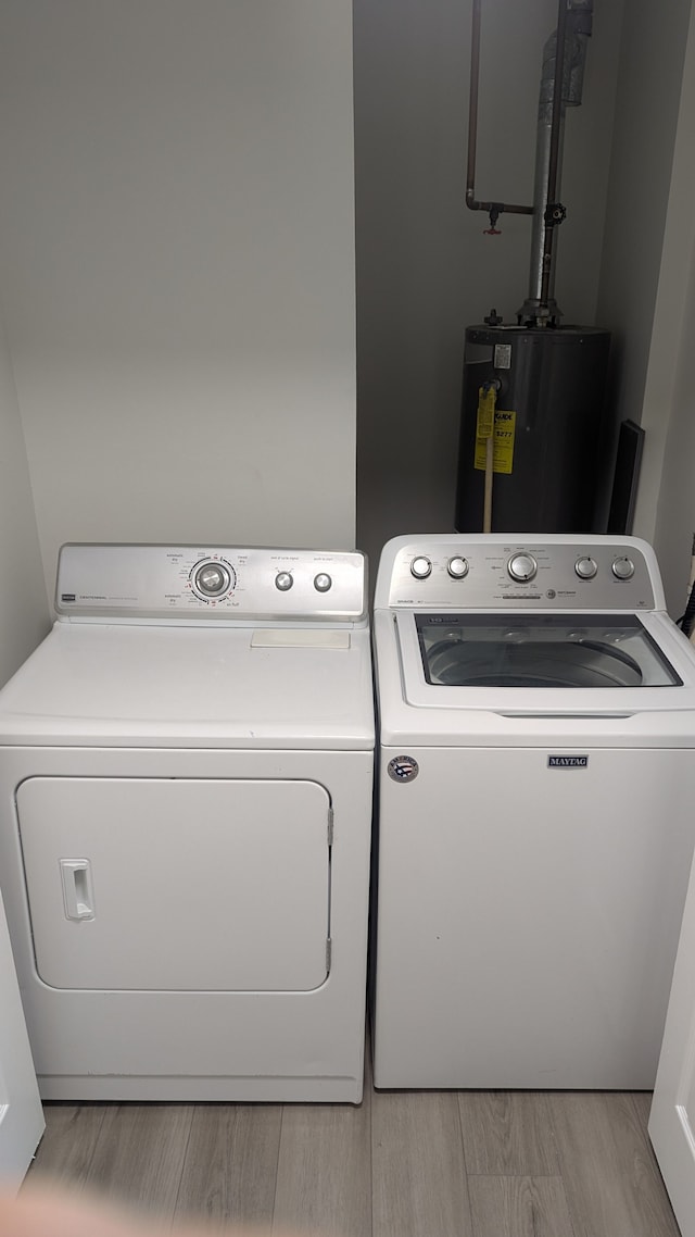 laundry area featuring light wood-type flooring, laundry area, water heater, and separate washer and dryer