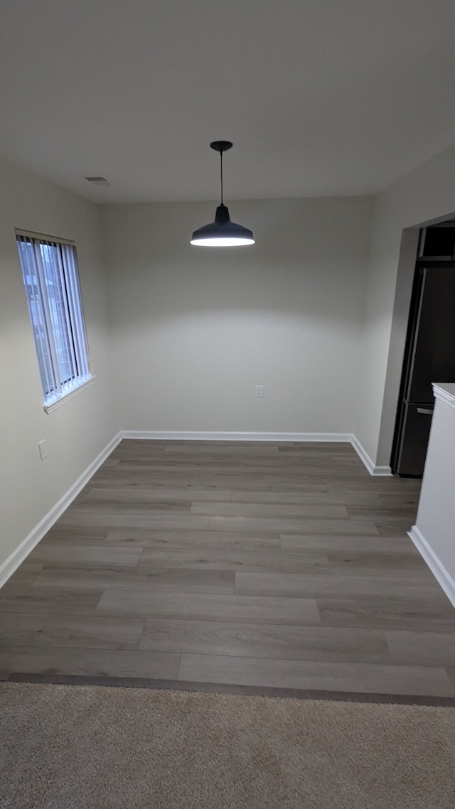 unfurnished dining area featuring visible vents, baseboards, and wood finished floors