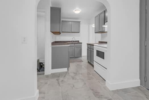 kitchen with a sink, marble finish floor, electric range, and gray cabinets