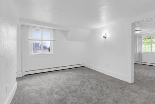 carpeted spare room with baseboards and a baseboard heating unit