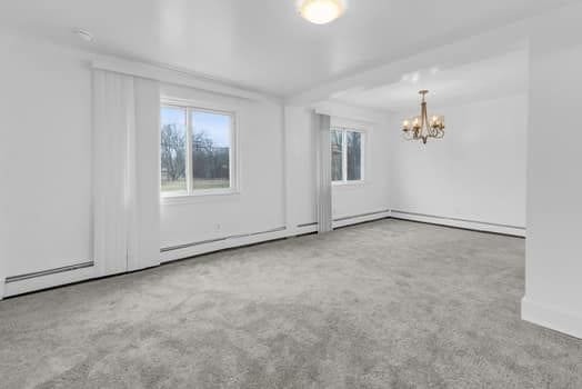 spare room featuring carpet floors and an inviting chandelier
