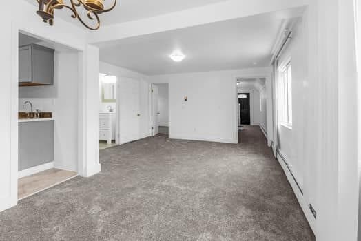 carpeted empty room with an inviting chandelier