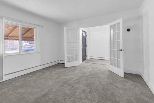 empty room with a baseboard radiator and french doors