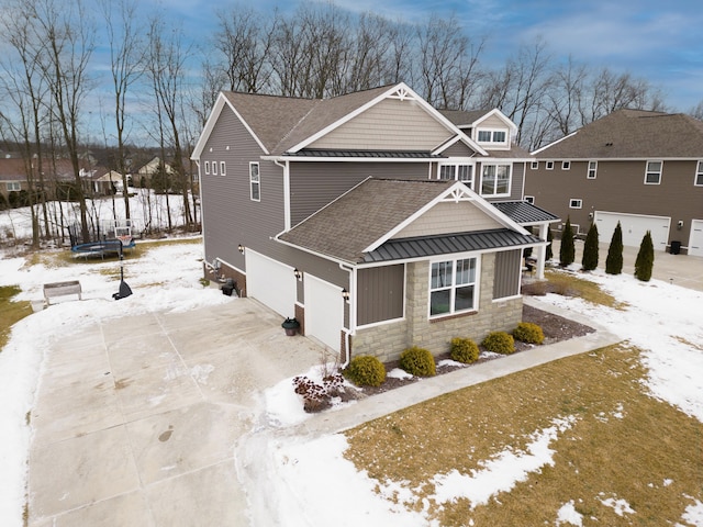 view of front facade featuring roof with shingles, an attached garage, a standing seam roof, metal roof, and stone siding