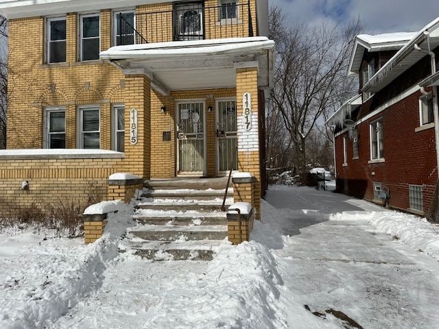 snow covered property entrance with brick siding