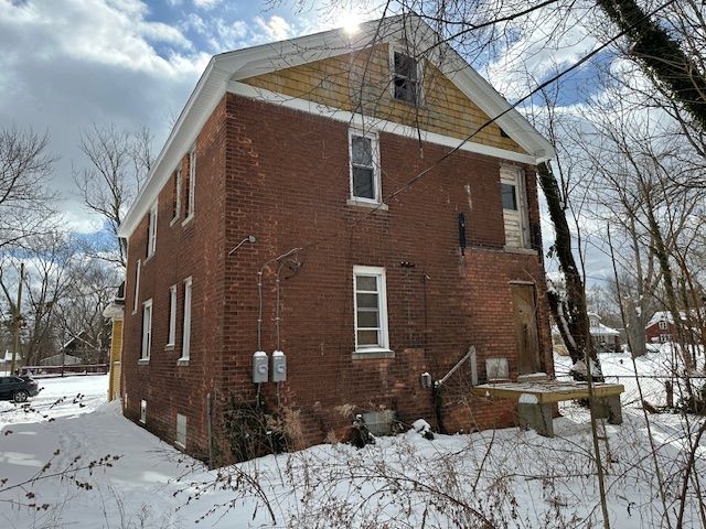 view of snow covered exterior with brick siding