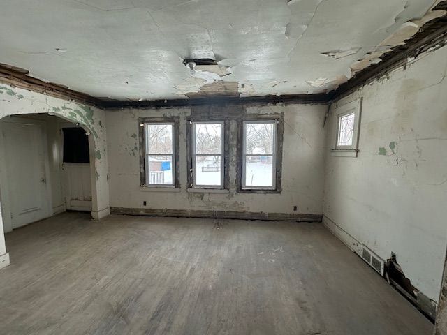 spare room with arched walkways, visible vents, and wood finished floors