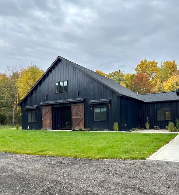 exterior space featuring metal roof, a front lawn, board and batten siding, and an outdoor structure