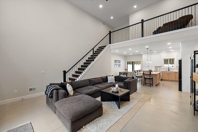 living area with recessed lighting, a towering ceiling, visible vents, and baseboards