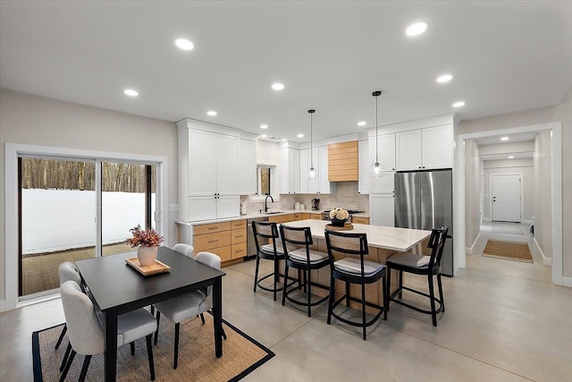 dining space with finished concrete floors, baseboards, and recessed lighting