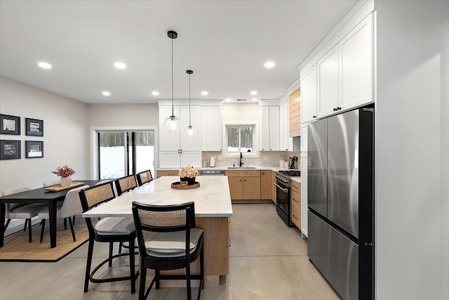 kitchen with a breakfast bar, a kitchen island, a sink, appliances with stainless steel finishes, and backsplash