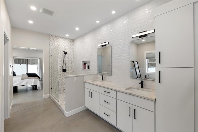 bathroom with concrete flooring, a sink, visible vents, tiled shower, and double vanity