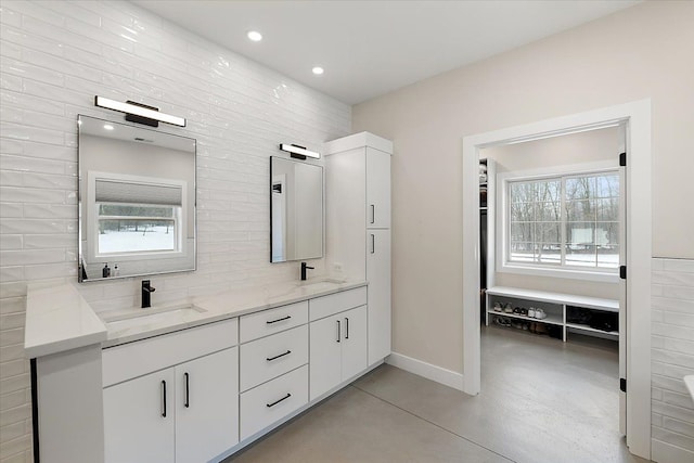 full bathroom featuring tasteful backsplash, a sink, baseboards, and double vanity