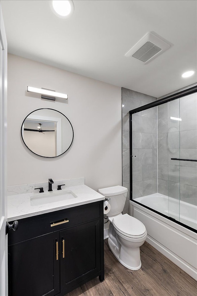 full bathroom featuring visible vents, toilet, enclosed tub / shower combo, vanity, and wood finished floors