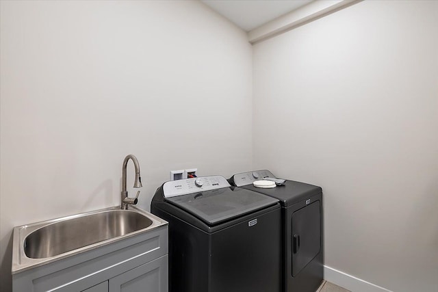 washroom featuring independent washer and dryer, a sink, cabinet space, and baseboards