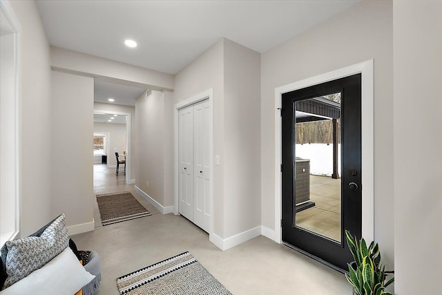 corridor with finished concrete floors, baseboards, and recessed lighting