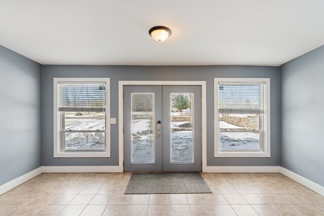 entryway with french doors, plenty of natural light, light tile patterned flooring, and baseboards