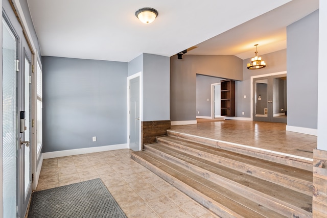 foyer with lofted ceiling, french doors, a chandelier, and baseboards