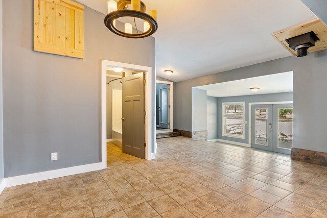 spare room with french doors, vaulted ceiling, baseboards, and light tile patterned floors