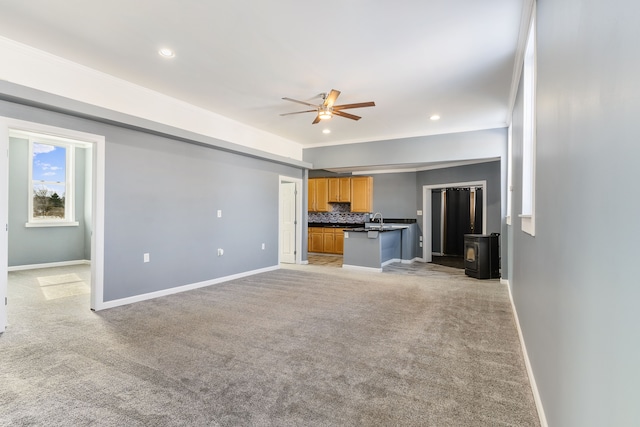 unfurnished living room with baseboards, light colored carpet, ceiling fan, a sink, and recessed lighting