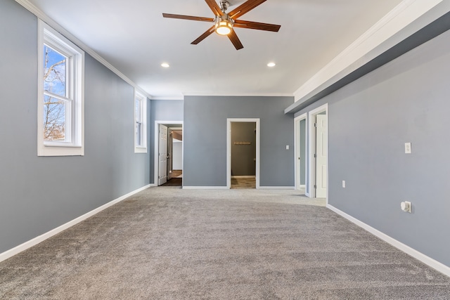 unfurnished bedroom featuring carpet floors, a spacious closet, baseboards, and crown molding