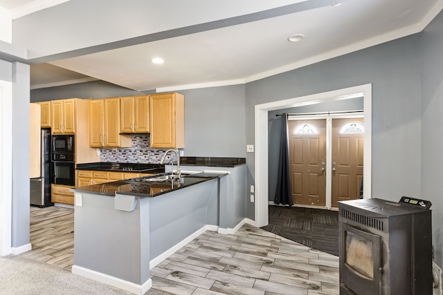 kitchen with crown molding, decorative backsplash, a sink, a peninsula, and black appliances