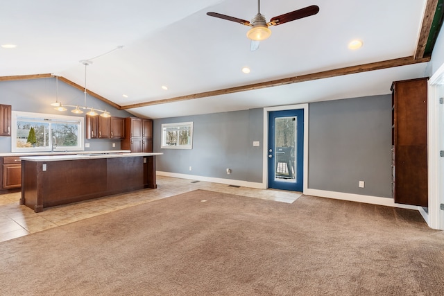 kitchen featuring light colored carpet, a kitchen island, open floor plan, light countertops, and pendant lighting