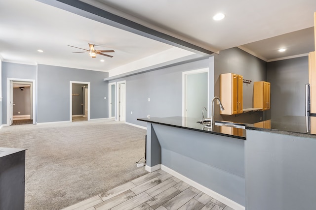 kitchen with a sink, baseboards, open floor plan, ornamental molding, and dark countertops