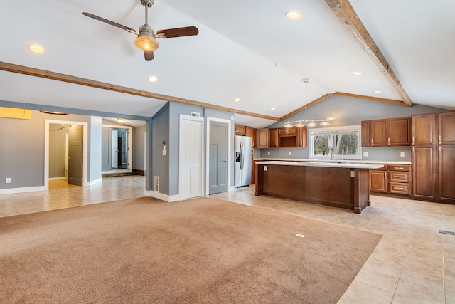 kitchen with a kitchen island, brown cabinets, light countertops, stainless steel refrigerator with ice dispenser, and pendant lighting