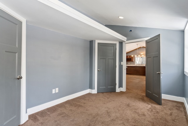 unfurnished bedroom with carpet, lofted ceiling, and baseboards