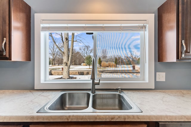 kitchen featuring a healthy amount of sunlight, dark brown cabinets, and a sink