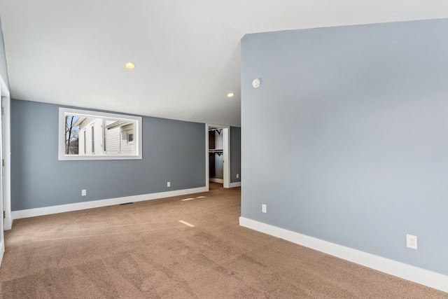 carpeted empty room with vaulted ceiling and baseboards