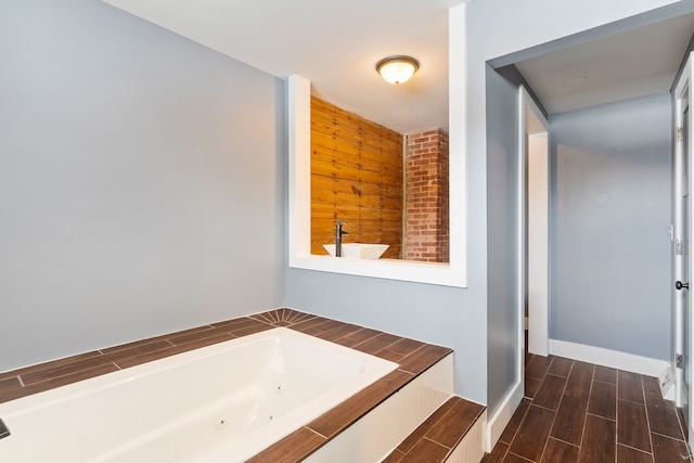 full bath featuring wood finish floors, baseboards, and a whirlpool tub