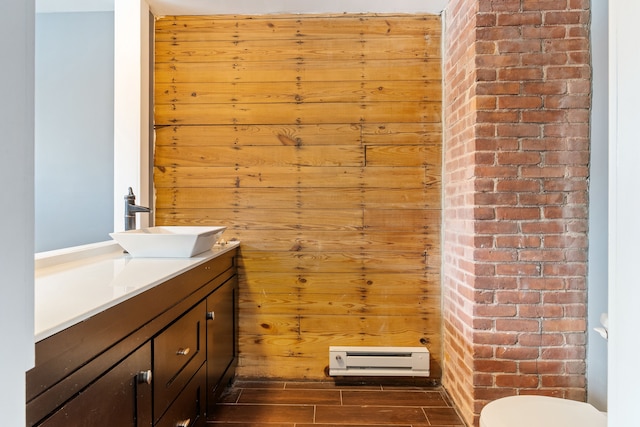 half bathroom with toilet, wood walls, wood finish floors, and vanity